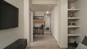 Un interno moderno con una TV a schermo piatto, una zona pranzo con due sedie e uno scaffale con un globo e un cartello con la scritta 'HOME'.