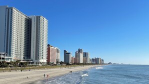 Un paisaje urbano costero con rascacielos, una playa de arena y el océano.