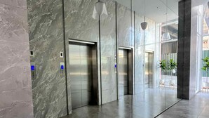 En moderne lobby med marmorvægge, to elevatorer og en glasvæg.