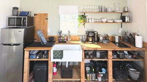 Cozinha compacta com geladeira, micro-ondas e cafeteira.