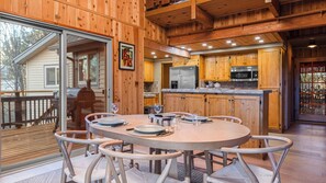 Ein Holzblockbau-Innenraum mit einem Esstisch, gedeckt für vier Personen, einer Küchenzeile mit Geräten und einer Glastür, die nach draußen führt.