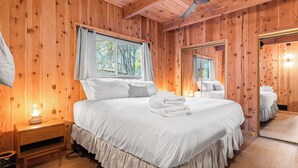 Ein Zimmer mit Holzwänden, einem Bett, einem Nachttisch und einem Spiegel.