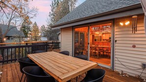 Eine Holzdar Terrasse mit Tisch und Stühlen, eine Glastür zu einer Küche und Blick auf die umliegende Gegend.