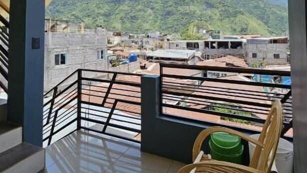 A balcony with a view of a mountainous landscape, a wooden chair, and a tiled floor. - Hotel Amanecer Atitlán (San Juan La Laguna)