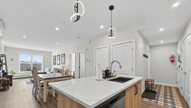 Een moderne keuken met een centraal eiland, witte kasten en hanglampen.