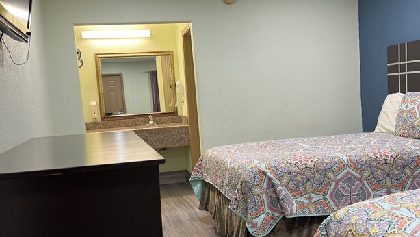 Ein Hotelzimmer mit Bett, Schreibtisch, Spiegel und Tür.