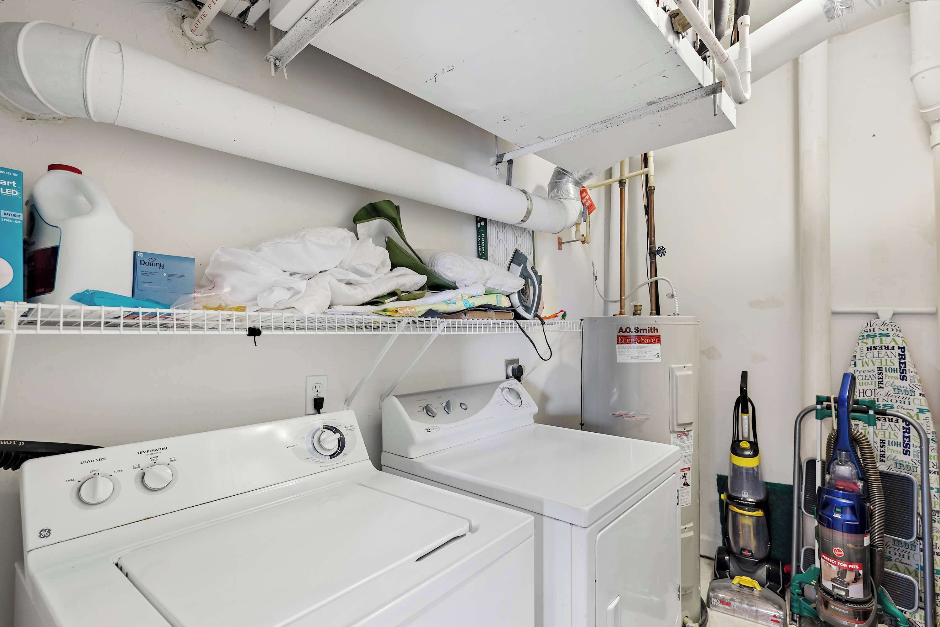 Un espace buanderie avec des piles de serviettes blanches, un sèche-linge et un aspirateur.