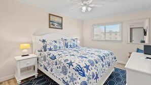 A bedroom with a bed, nightstand, desk, and ceiling fan. - Salty Sands 4 208 (Ocean City)