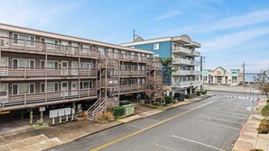 A multi-story building with a fire escape, a parking lot, and a view of the ocean. - Salty Sands 4 208 (Ocean City)