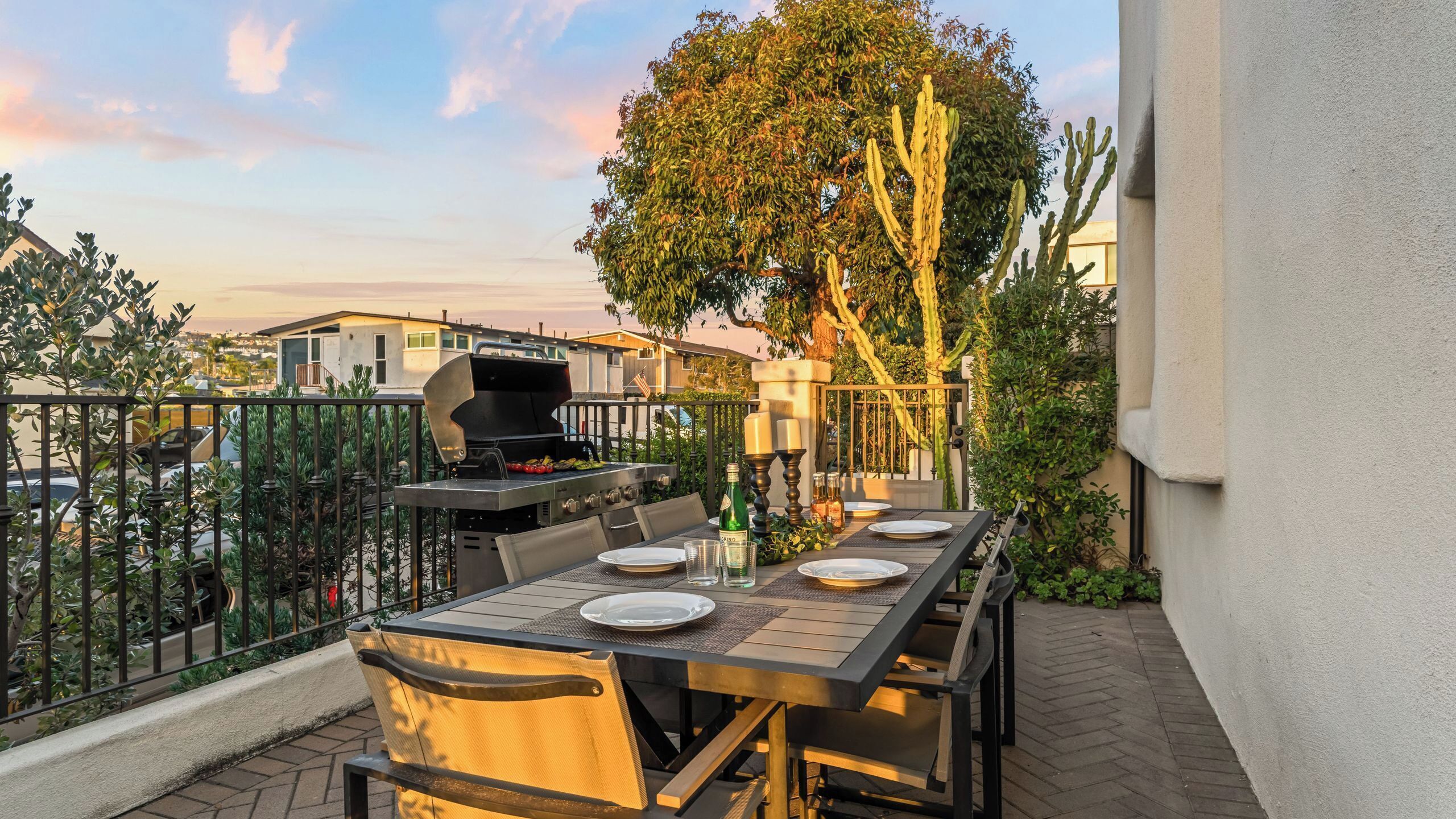 Une terrasse extérieure équipée d’un barbecue, d’une table à manger, de chaises et offrant une vue sur le quartier.