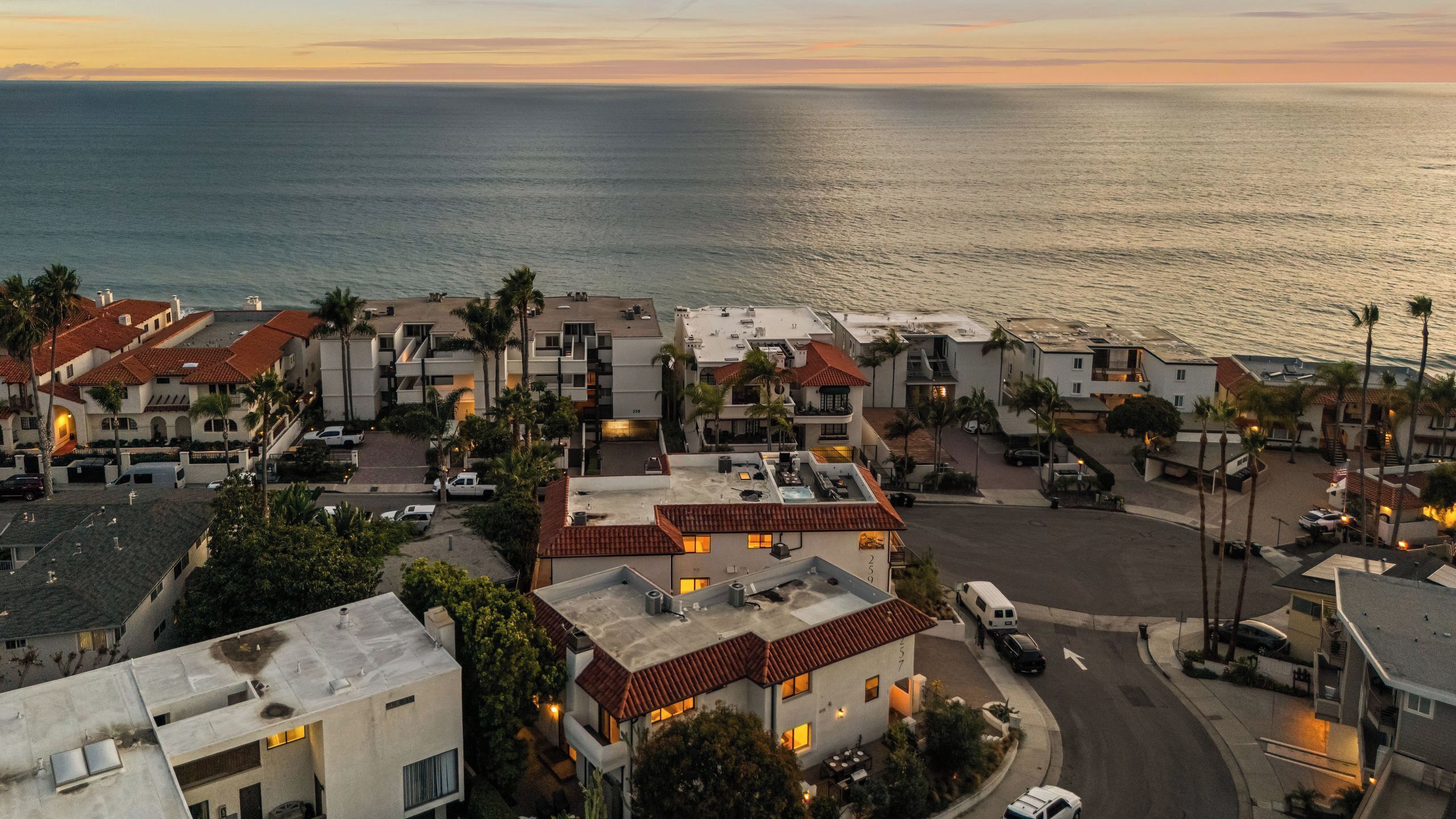 Un quartier résidentiel en bord de mer, avec des maisons aux toits recouverts de tuiles rouges, dont certaines sont dotées de balcons, et qui offrent une vue sur l’océan.