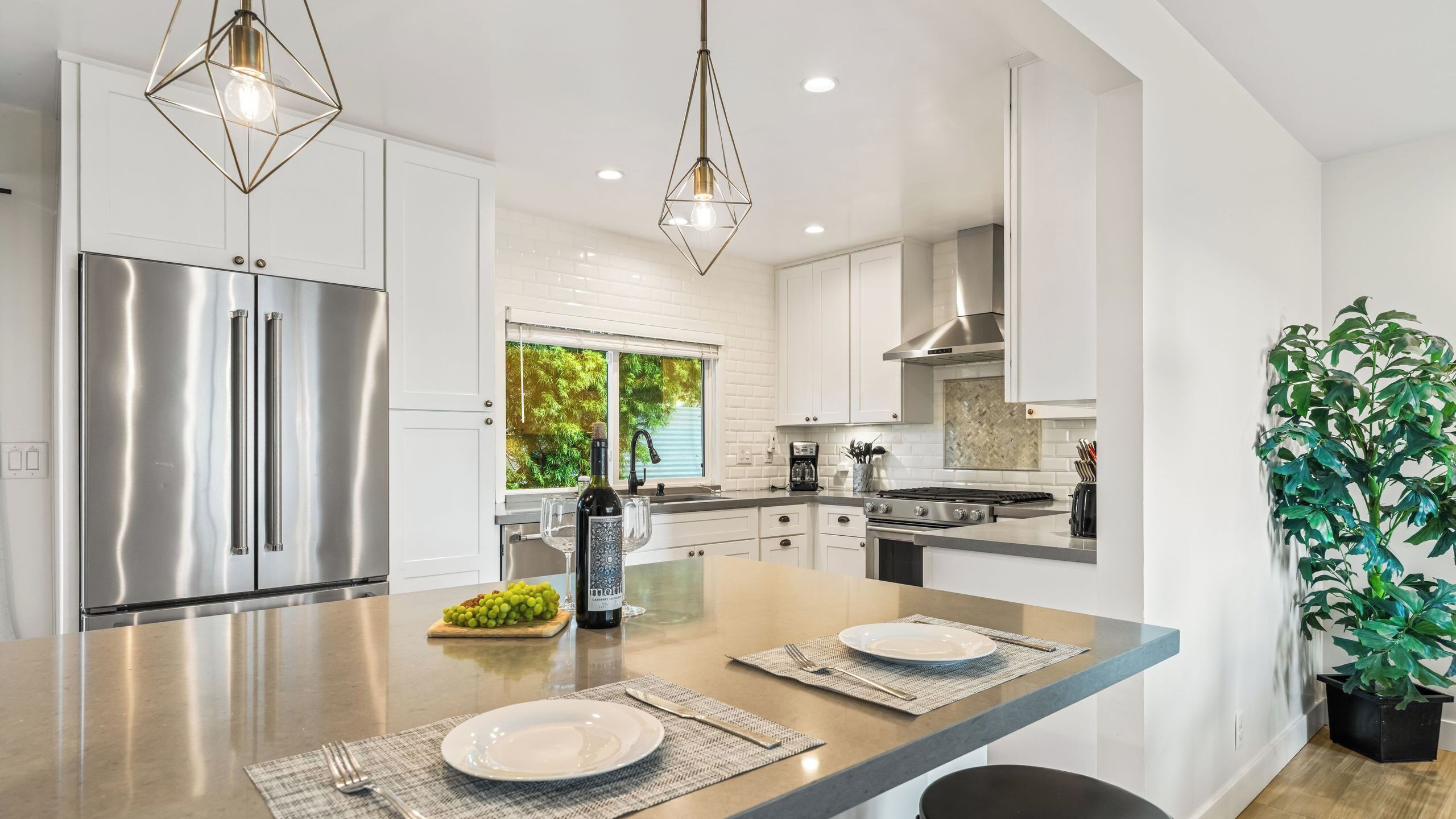 A modern kitchen with stainless steel appliances, a central island with seating, and a large window providing natural light.