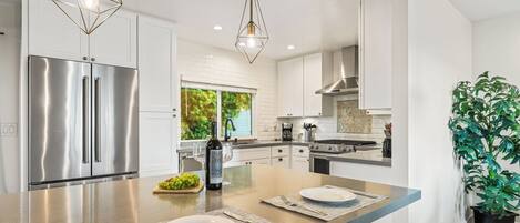 A modern kitchen with stainless steel appliances, a central island with seating, and a large window providing natural light.