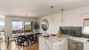 A modern kitchen with a marble countertop, a dining area with a view, and a large mirror. - Rooftop w/ Hot Tub, Ocean Views 259 Trailhead Trestles 1 by Avantstay (San Clemente)
