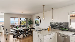 A modern kitchen with a marble countertop, a dining area with a view, and a large mirror.