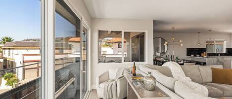 A modern living room with a sofa, a coffee table, and a dining area with a kitchen in the background.