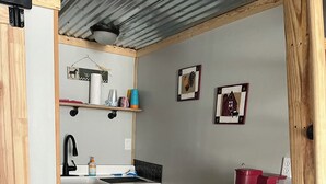 Una cocina compacta con un lavamanos, microondas y estantes de almacenamiento.