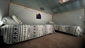 Una habitación con dos camas, cada una con ropa de cama estampada. Encima de las camas, hay un cuadro pequeño en la pared.