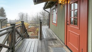 A wooden deck leading to a red door with a window, a metal railing, and a view of a forested area. - 2 bedroom beautiful apartment in åre (Åre)