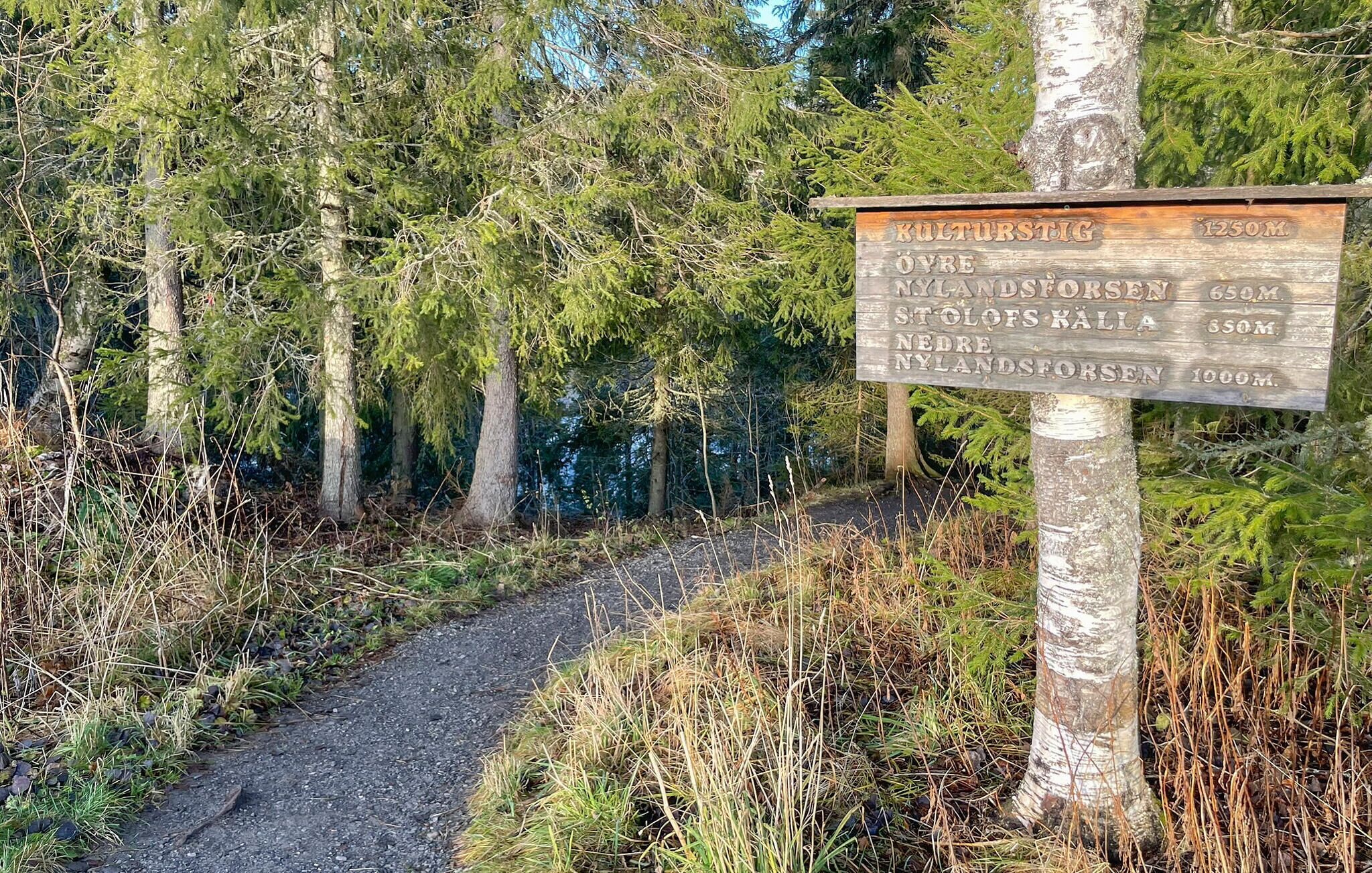 A wooden signpost with distance markers for various locations.