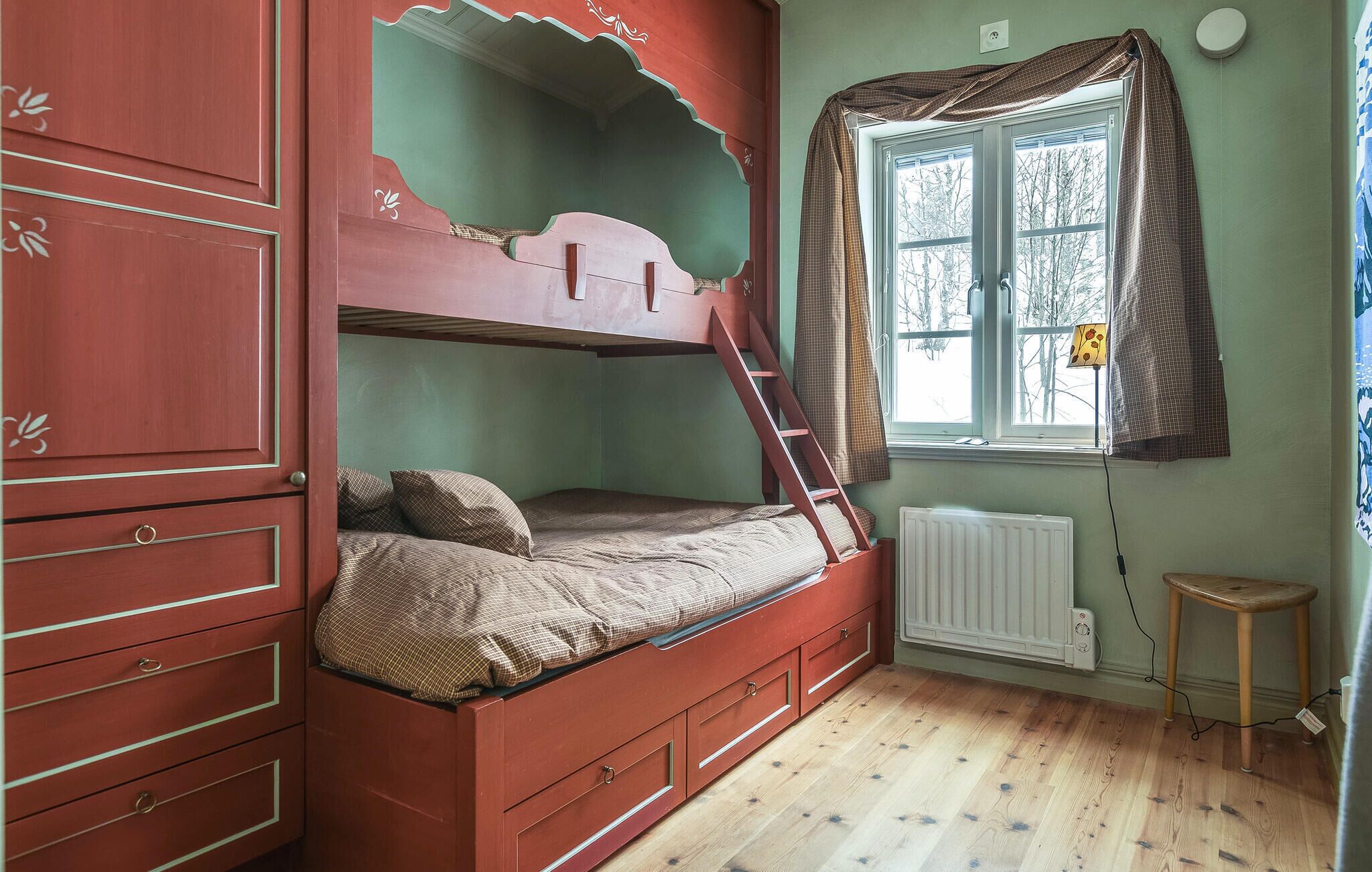 Une chambre avec un lit superposé, une échelle, une fenêtre avec des rideaux, un radiateur et un petit tabouret.