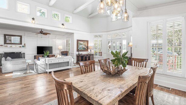 A spacious living area with a wooden dining table, white cabinetry, and a large window with shutters. - Sunshine, Seaside and Nobellah's Retreat/ Pet Friendly/ 4 Bikes (Santa Rosa Beach)