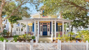 A white picket fence surrounding a yellow house with a blue door and white columns. - Sunshine, Seaside and Nobellah's Retreat/ Pet Friendly/ 4 Bikes (Santa Rosa Beach)