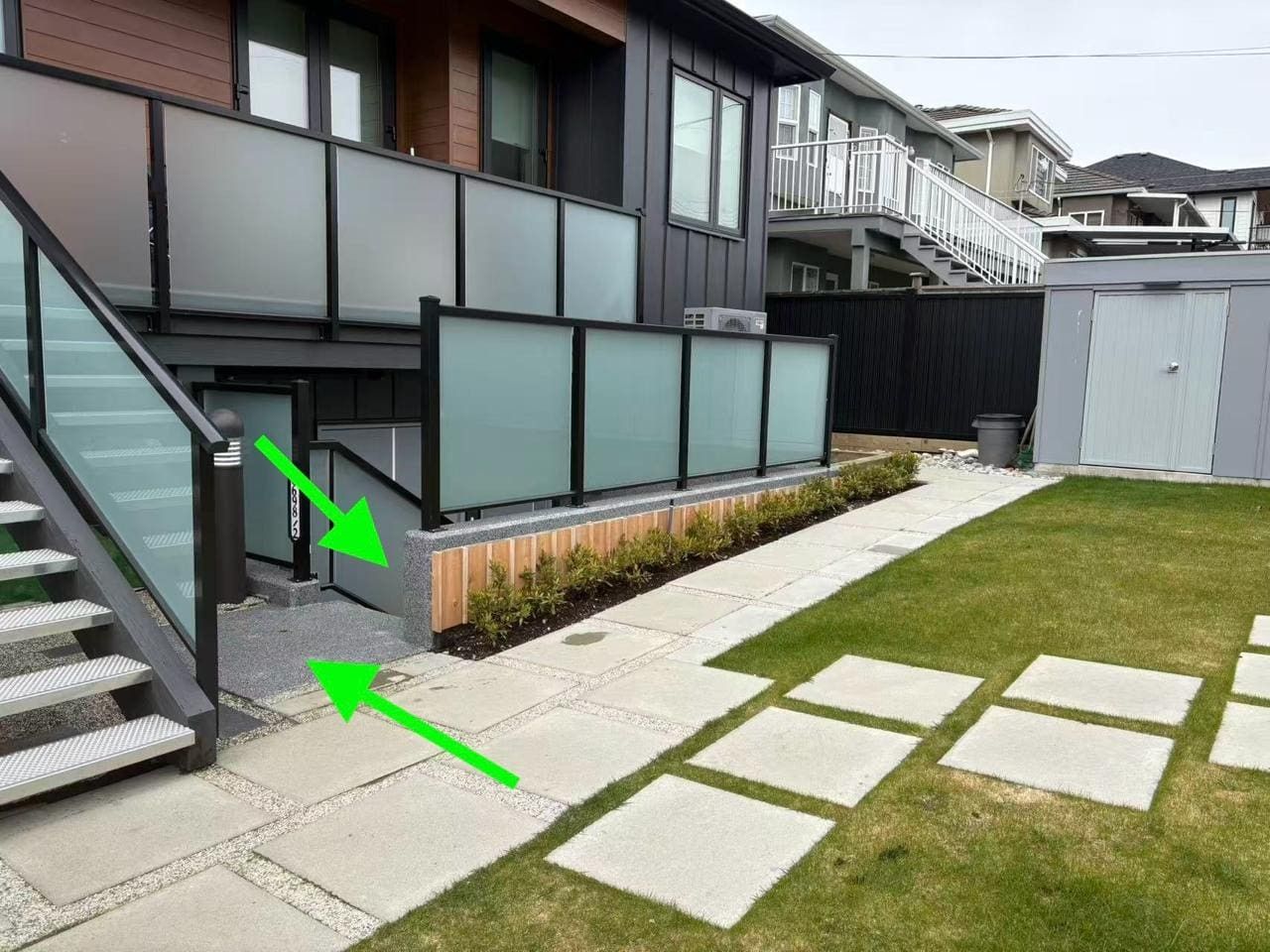 A modern two-story house with a visible staircase leading to the entrance, a well-maintained lawn, and a pathway with stepping stones.