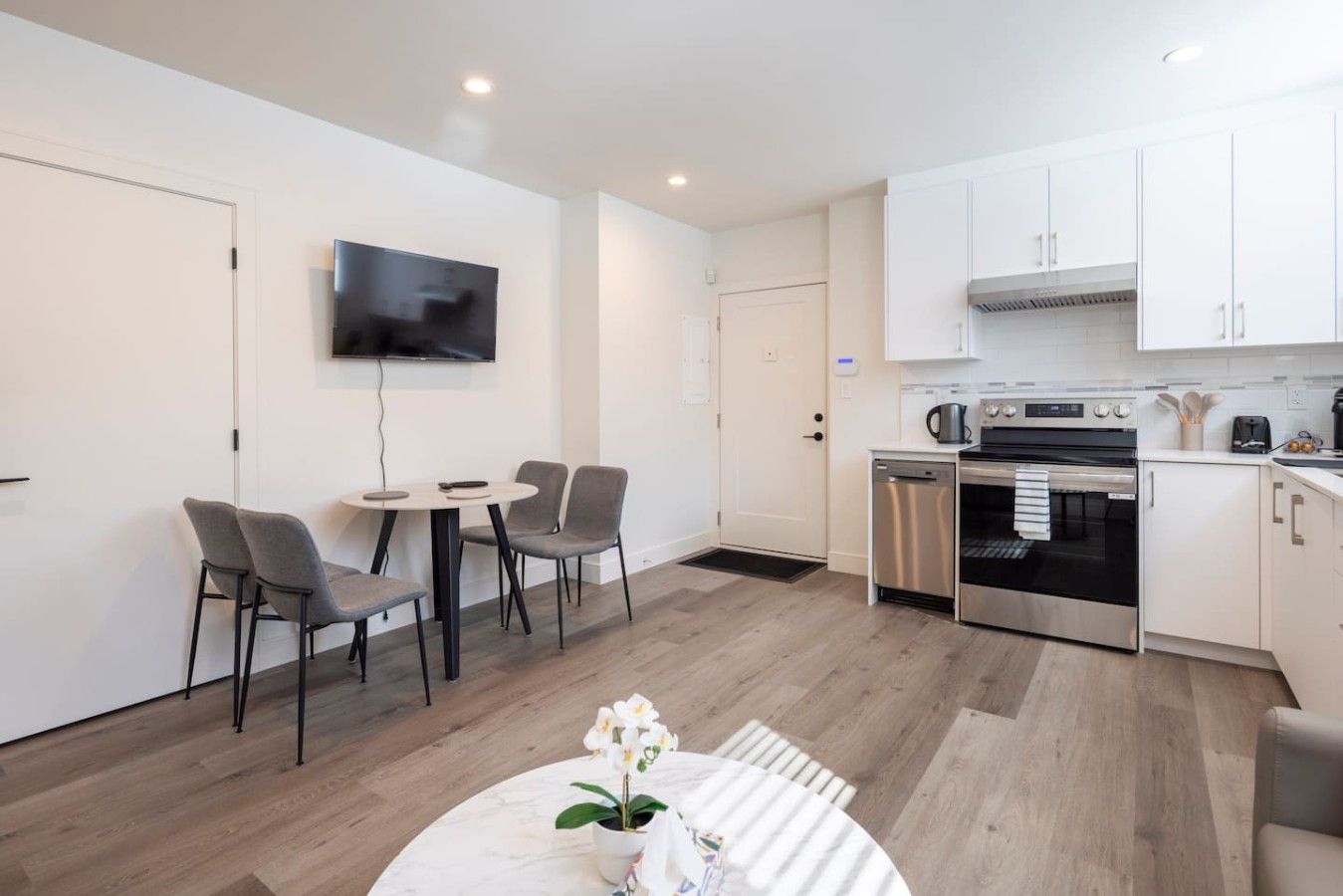 A modern kitchen with white cabinets, a built-in oven, and a dishwasher.
