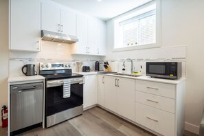 A modern kitchen with stainless steel appliances, white cabinetry, and a window above the sink.
