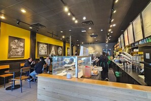 Interior de un restaurante con mesas, una barra y una pizarra de menú.