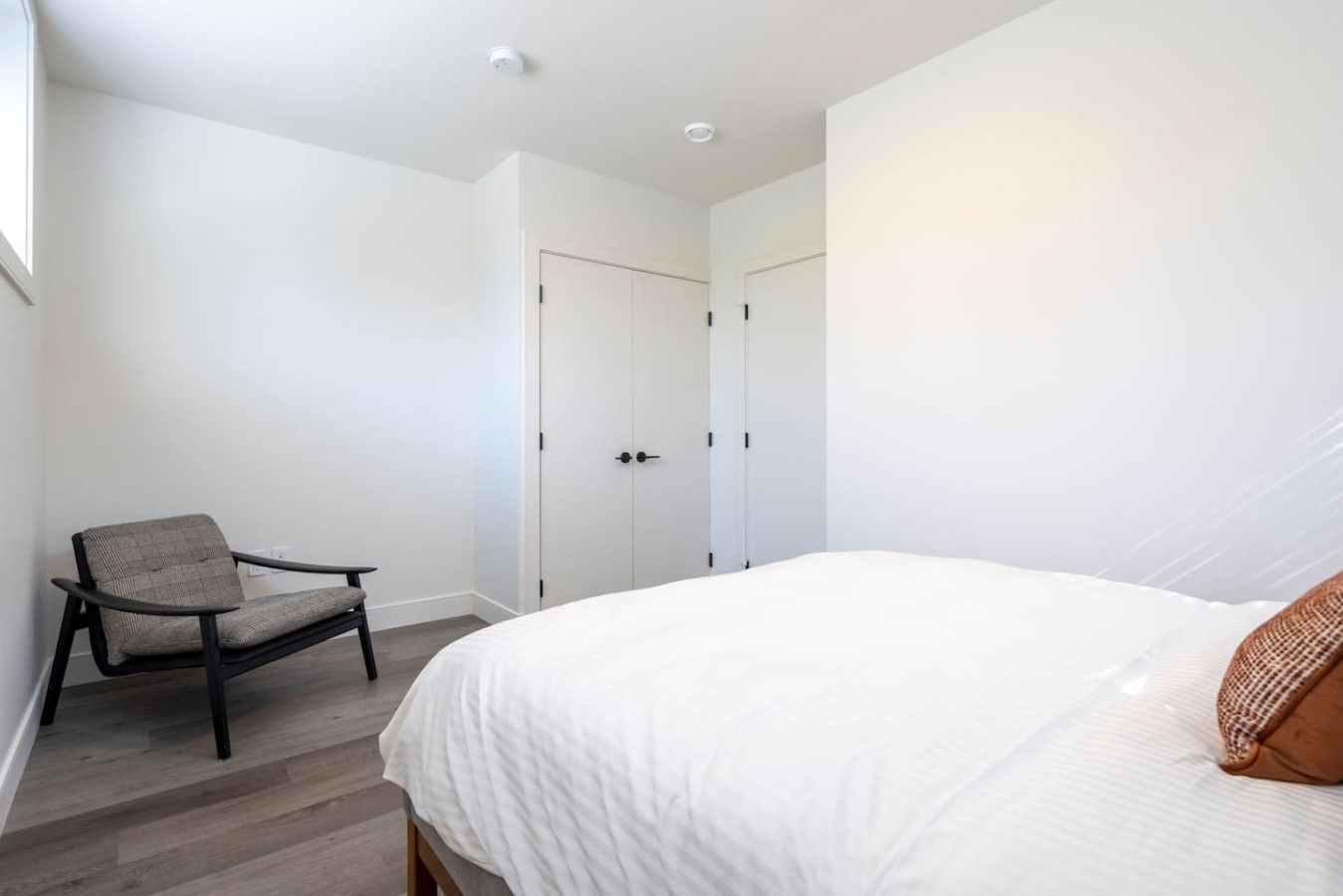 A bedroom with a bed, a chair, and a wardrobe.