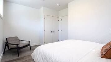 A bedroom with a bed, a chair, and a wardrobe.
