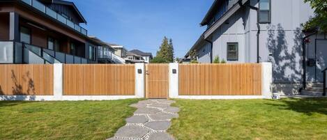 Un quartier résidentiel moderne doté d’une entrée sécurisée, d’un chemin pavé et de bâtiments adjacents avec de grandes fenêtres et des balcons.