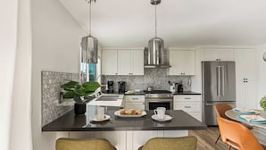 A modern kitchen with white cabinets, stainless steel appliances, and a central island with seating. - Walk to Beach Hot Tub + Oceanview Deck 259 Trailhead Trestles 2 by Avantstay (San Clemente)