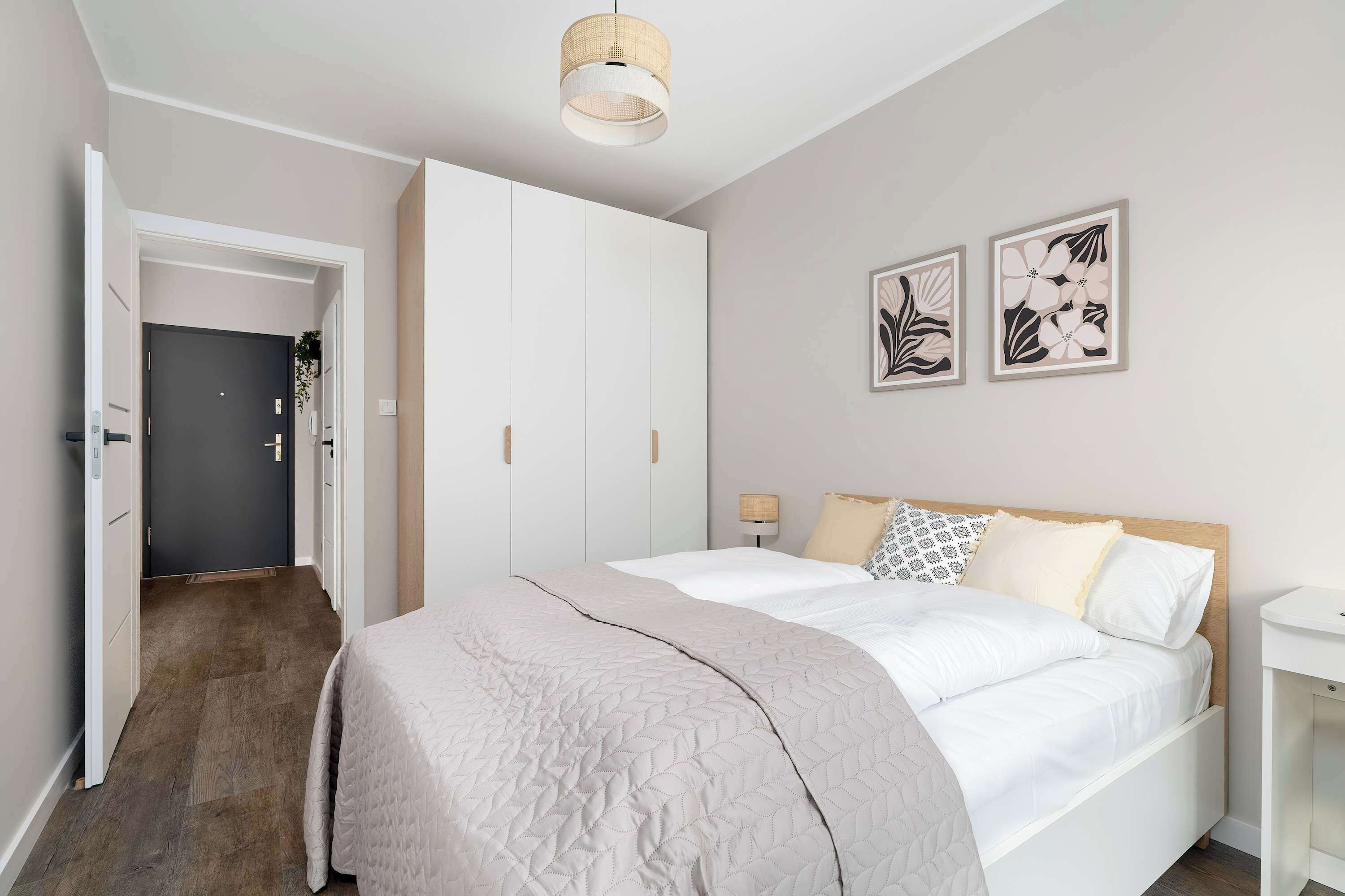 Quarto com cama, guarda-roupa, mesa de cabeceira e duas obras de arte na parede.