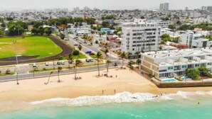 A coastal cityscape with a beach, a sports field, and modern buildings. - Ocean Park 3BD+2BA Pool Walk to beach @Portocafe (San Juan)