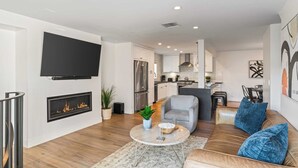 A modern living room with a fireplace, a TV, and a sofa. - Steps to Beach, Hot Tub + Private Patio 259 Trailhead Trestles 3 by Avantstay (San Clemente)