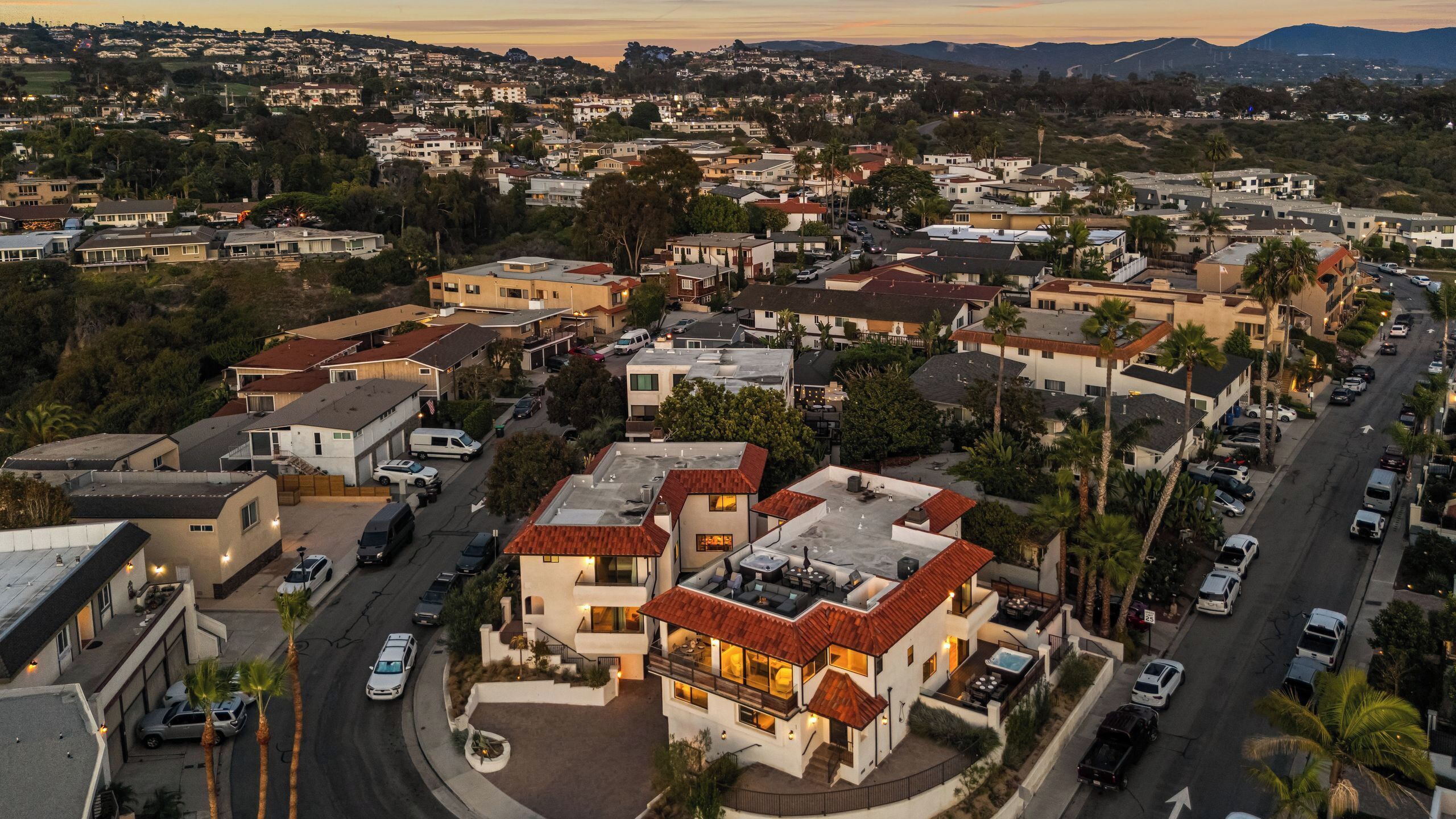 A residential area with houses, a street, and a large building with a pool and outdoor seating.