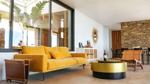 Ein modernes Wohnzimmer mit einem gelben Sofa, einem runden Couchtisch und einer Steinwand.