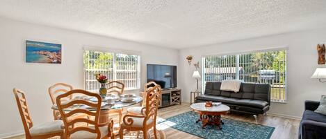 A spacious living room with a dining area, a sofa, and a TV.