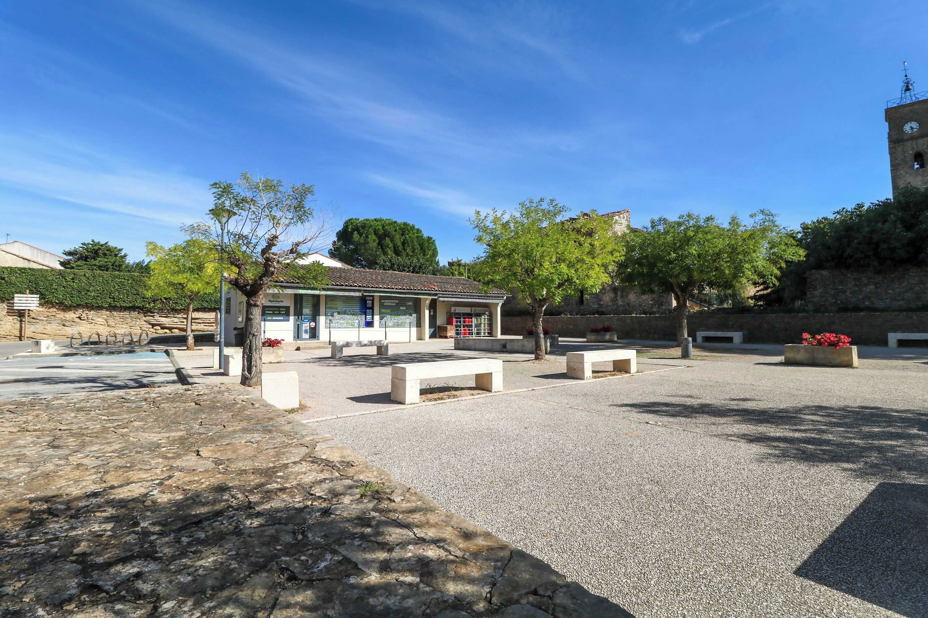 A courtyard with a small building, benches, and a stone wall.
