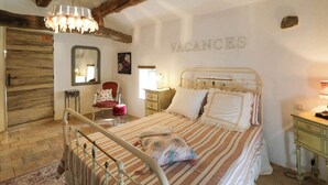 Une chambre à coucher comprenant un lit, une table de chevet, une chaise, un miroir et un panneau mural sur lequel on peut lire le mot « VACANCES ».