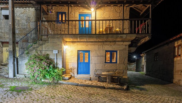 A two-story stone building with a balcony, a blue door, and a cobblestone courtyard. - Casa do Sarracas (Montalegre)