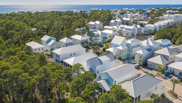 A coastal residential area with modern houses, a swimming pool, and dense pine trees. - Constant Getaway by Avantstay 30A Coastal Retreat Outdoor Lounge, Golf Cart, Bikes + Near Beach (Santa Rosa Beach)