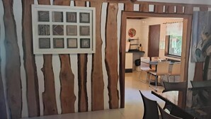 A room with a wooden wall, a framed picture, and a dining area with chairs and a table.