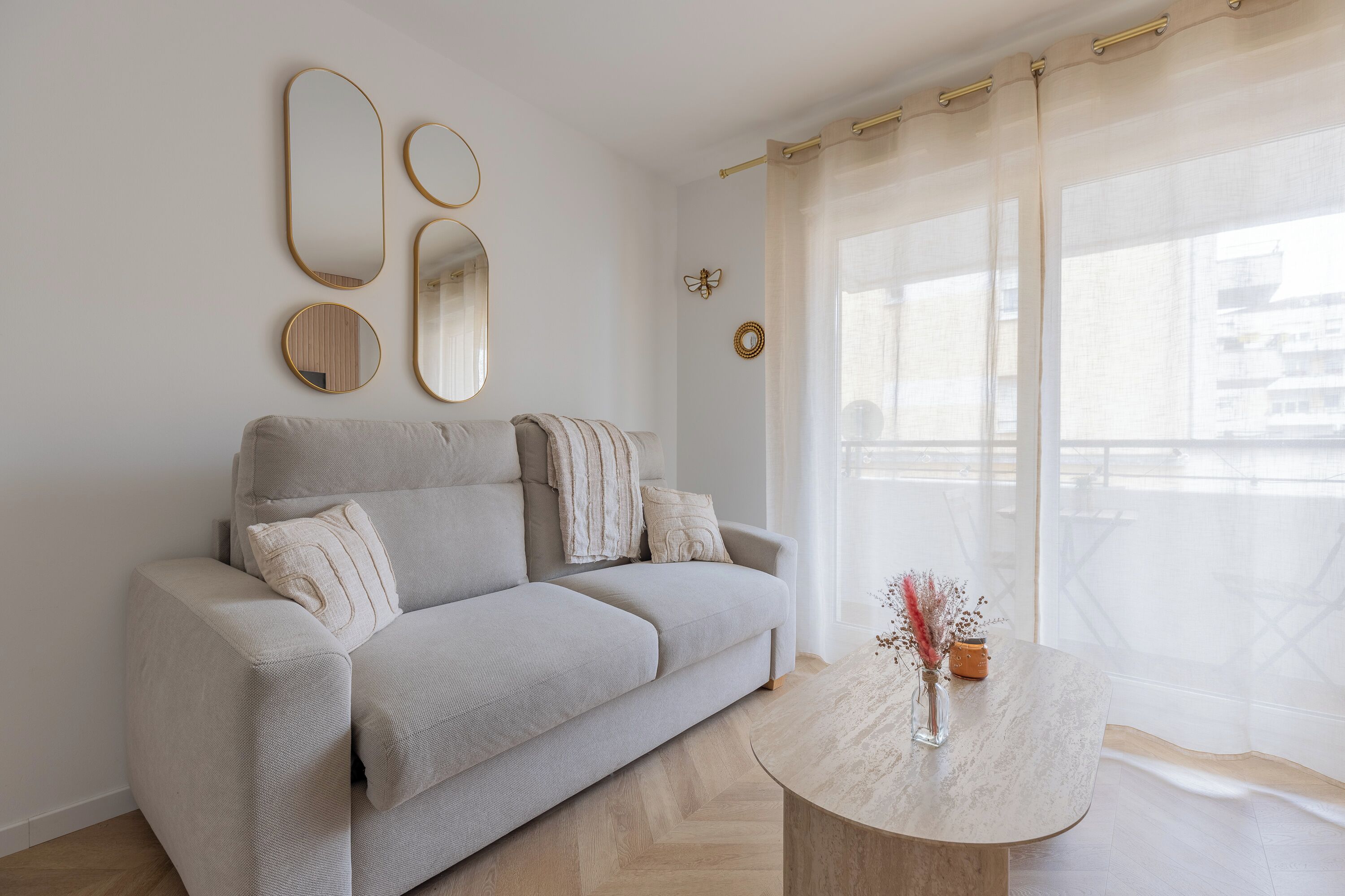 Un soggiorno moderno con divano, tavolino e specchi decorativi alle pareti.