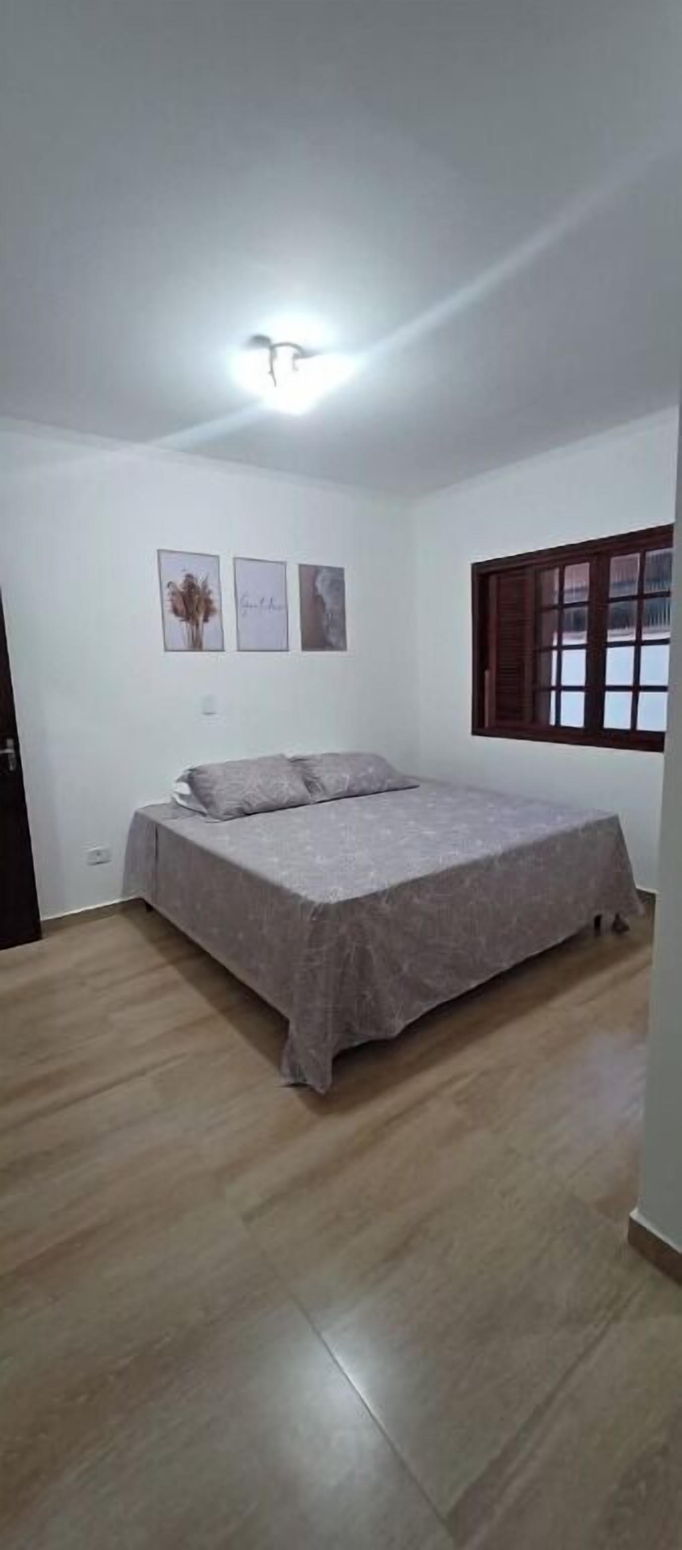 Ein Schlafzimmer mit Bett, Holzboden, weißen Wänden und einem Fenster mit Holzjalousien.