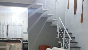 Ein Wohnzimmer mit einer Couch, ein Essbereich mit Tisch und Stühlen sowie eine Treppe mit Geländer.