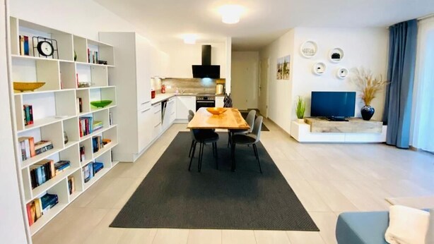 En moderne stue med spiseplads, køkken og TV.